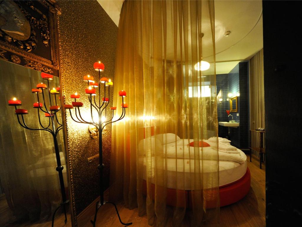Hotelzimmer mit Rundbett, Baldachin, Kerzenständer und offenem Bad.
